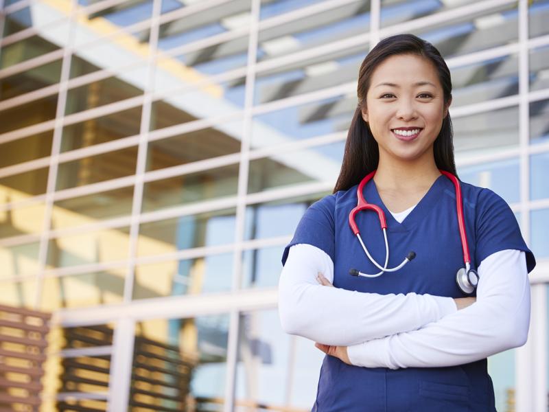 Smiling Asian female healthcare worker with arms crossed